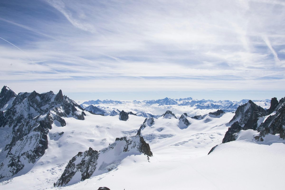 A hardcore freerider navigating a steep high-alpine spine wall, demonstrating the advanced snowboard engineering of S-ONE in late-season conditions.